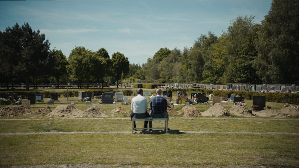 Zwei Männer sitzen auf einer Bank auf dem Friedhof