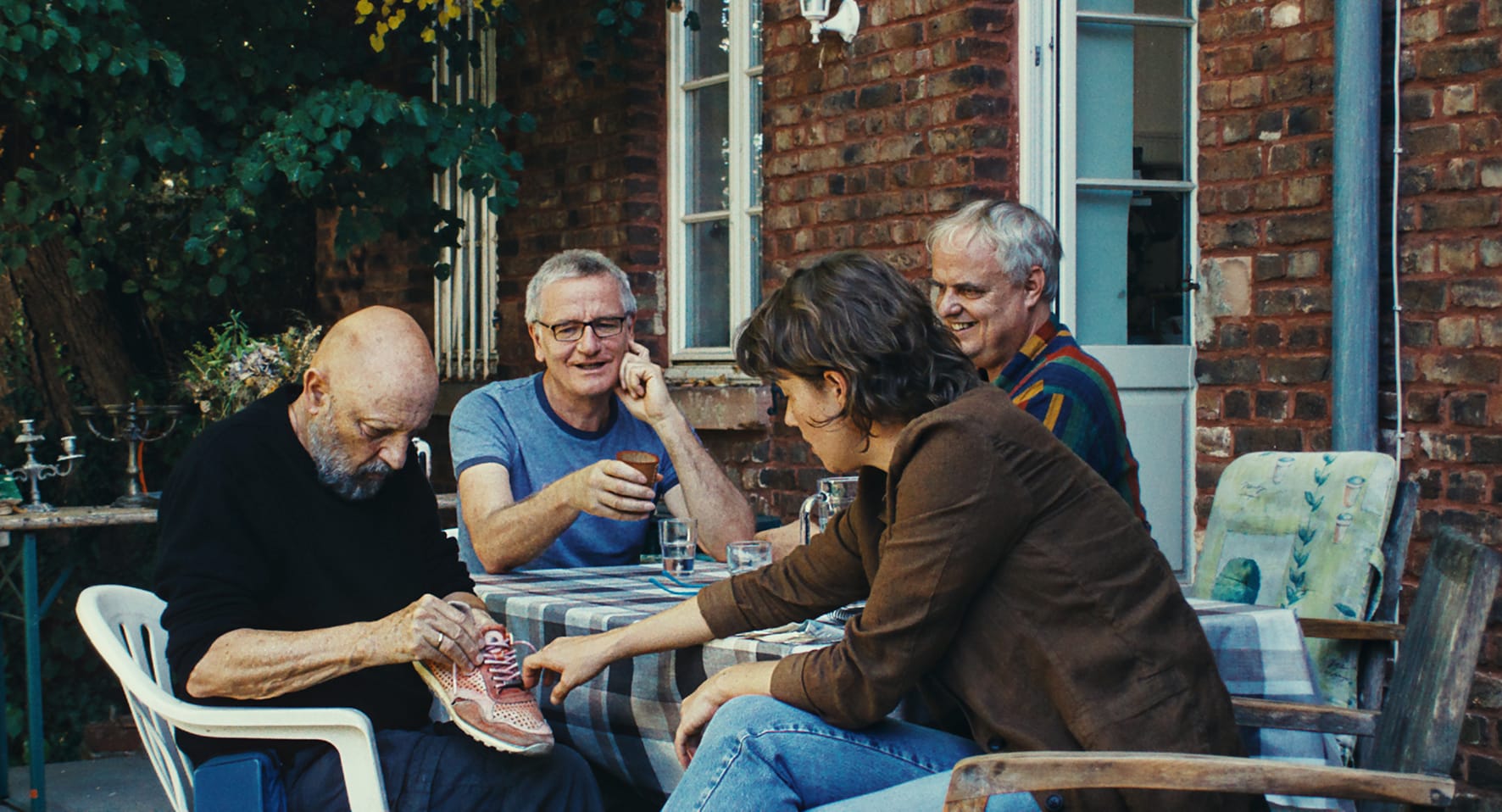 Vier Personen sitzen an einem Tisch im Hof.