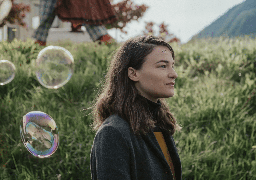 Seitenansicht einer Frau in der Natur, davor Seifenblasen